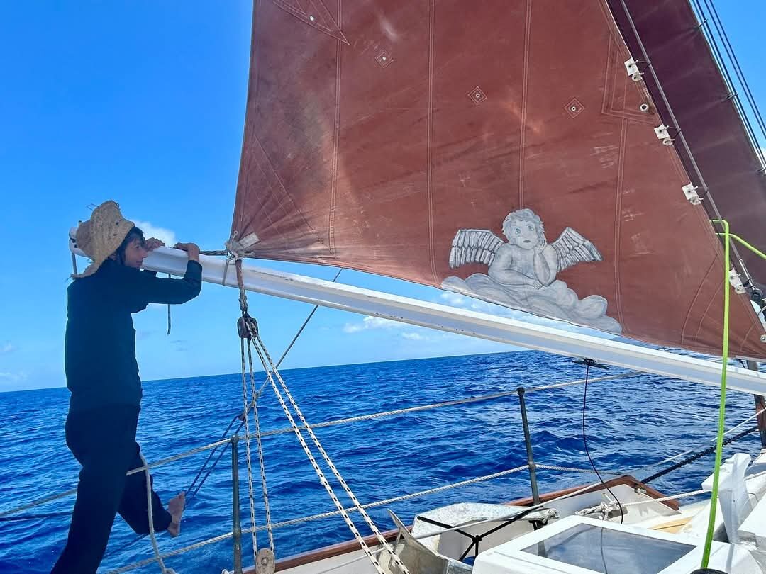 Angela Wolf at the bow of Cherub, straw hat, at sea
